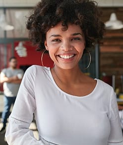 Smiling Young African Businesswoman With People In Background